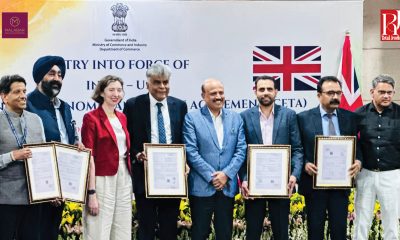 Government officials and industry representatives mark the entry into force of the India–UK CETA while holding framed trade documents.