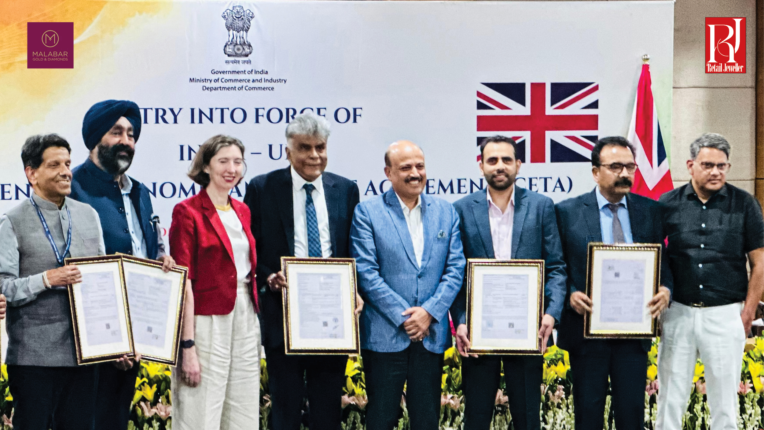 Government officials and industry representatives mark the entry into force of the India–UK CETA while holding framed trade documents.